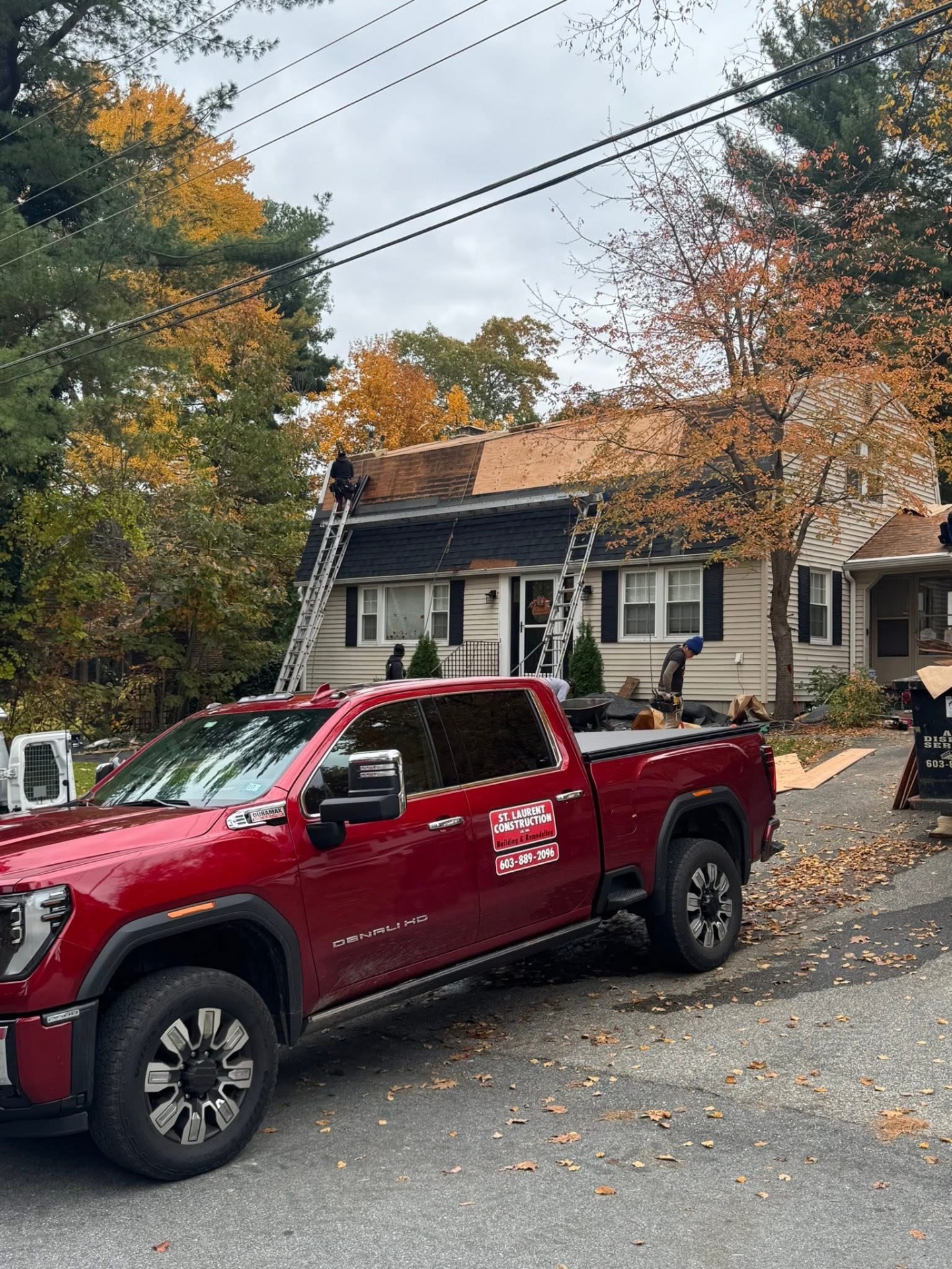 Decking complete — fresh plywood sheathing across the front slope, ready for ice-and-water shield and underlayment, with the St. Laurent Construction truck on site.