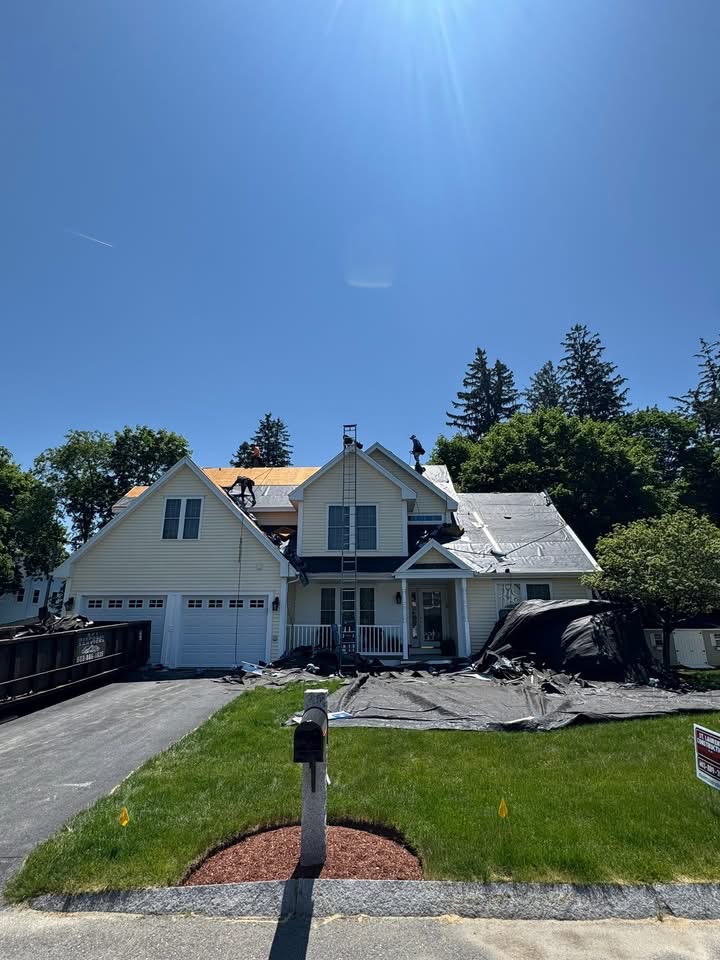 In progress — tear-off down to the deck with new underlayment going on and crew working the ridge.