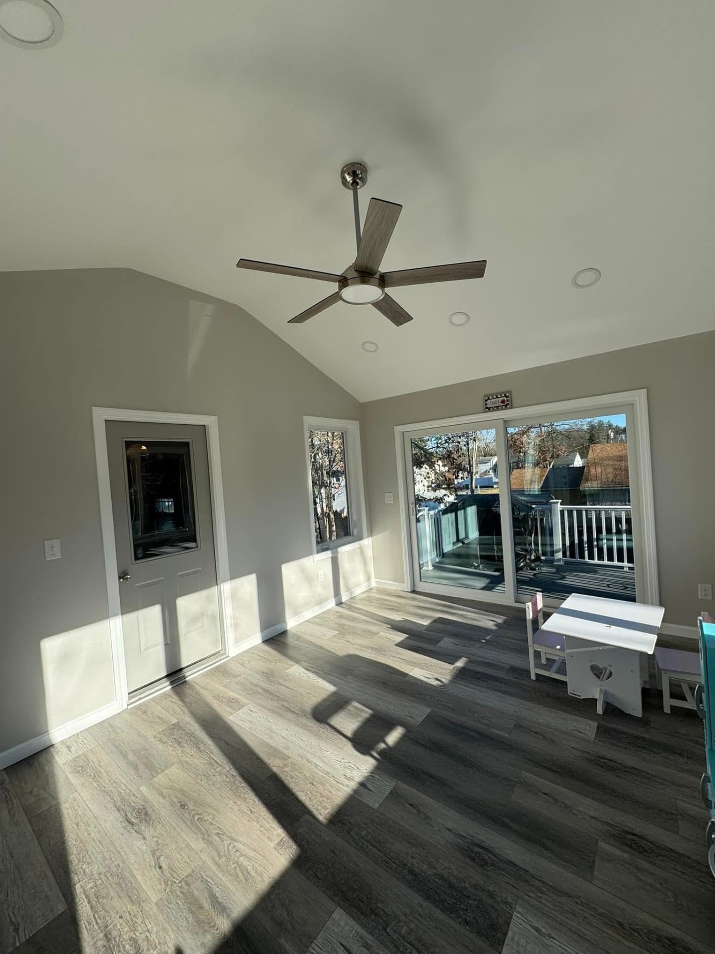 Adjacent room — cathedral ceiling, ceiling fan, and slider out to the new deck.