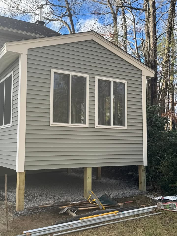Side gable end — vertical white trim and large double windows set in gray siding.