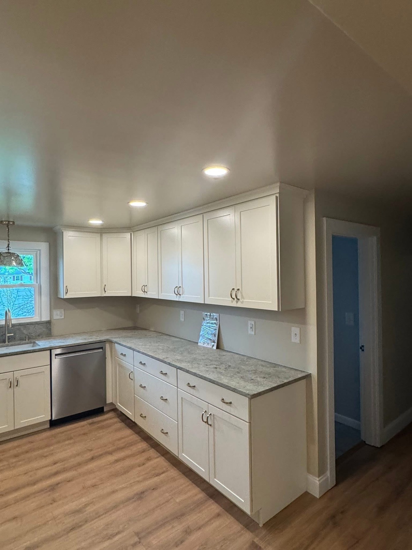 Dishwasher run and corner uppers with granite counters, cabinets built to the ceiling, and new LVP flooring.