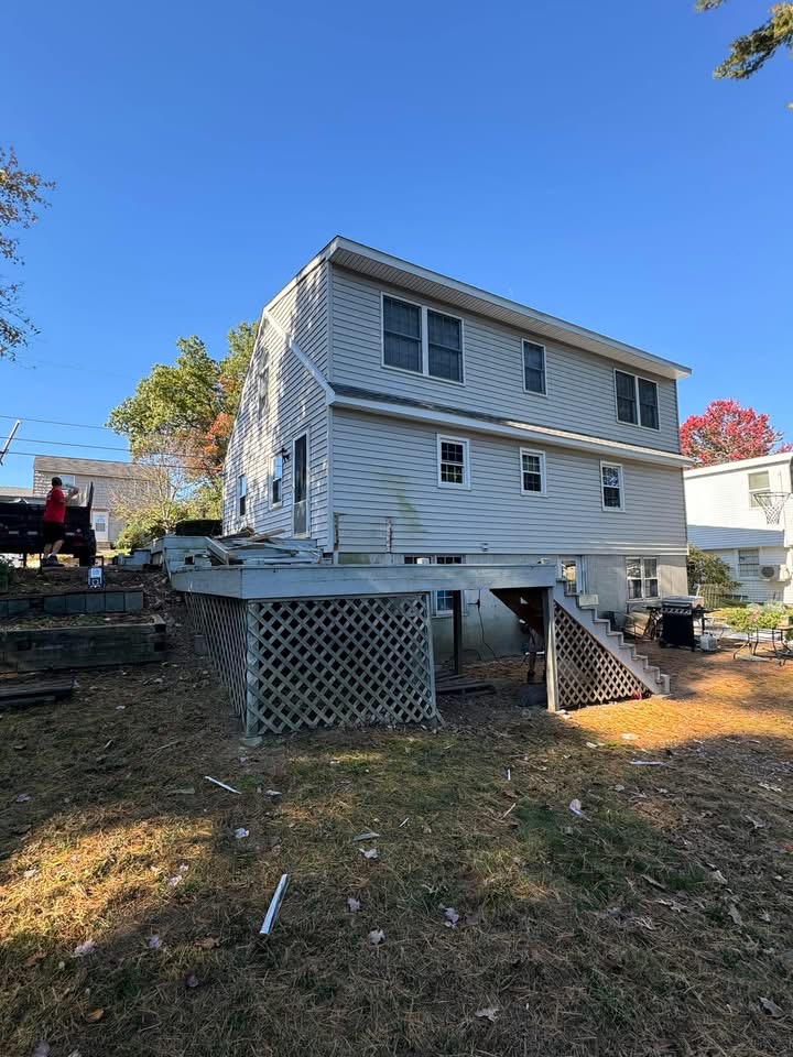Before — back of the home showing the old lattice-skirted deck we removed.