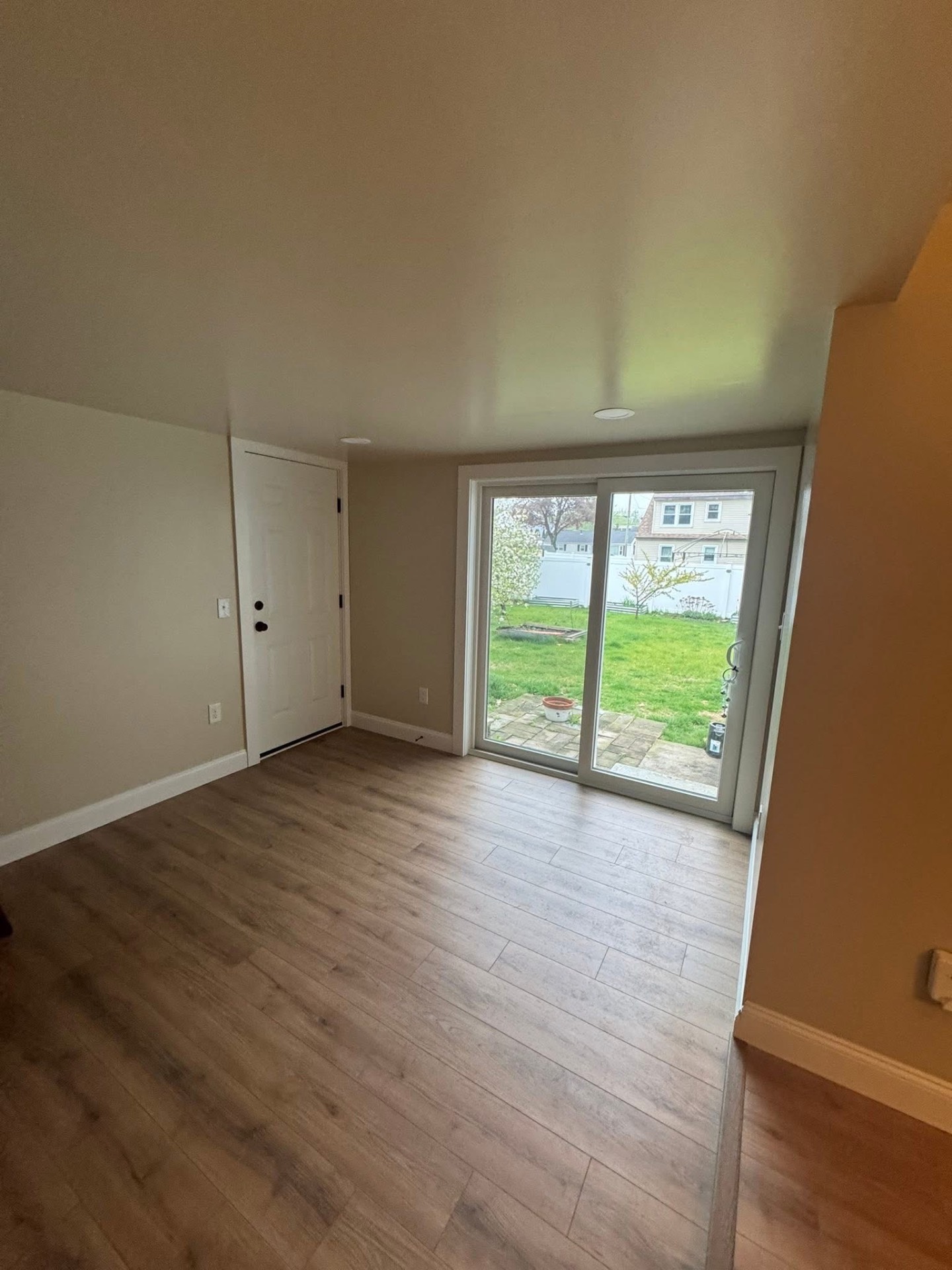 Finished mudroom entry off the kitchen with a fresh exterior door, new slider out to the backyard, and matching LVP flooring, trim, and paint.