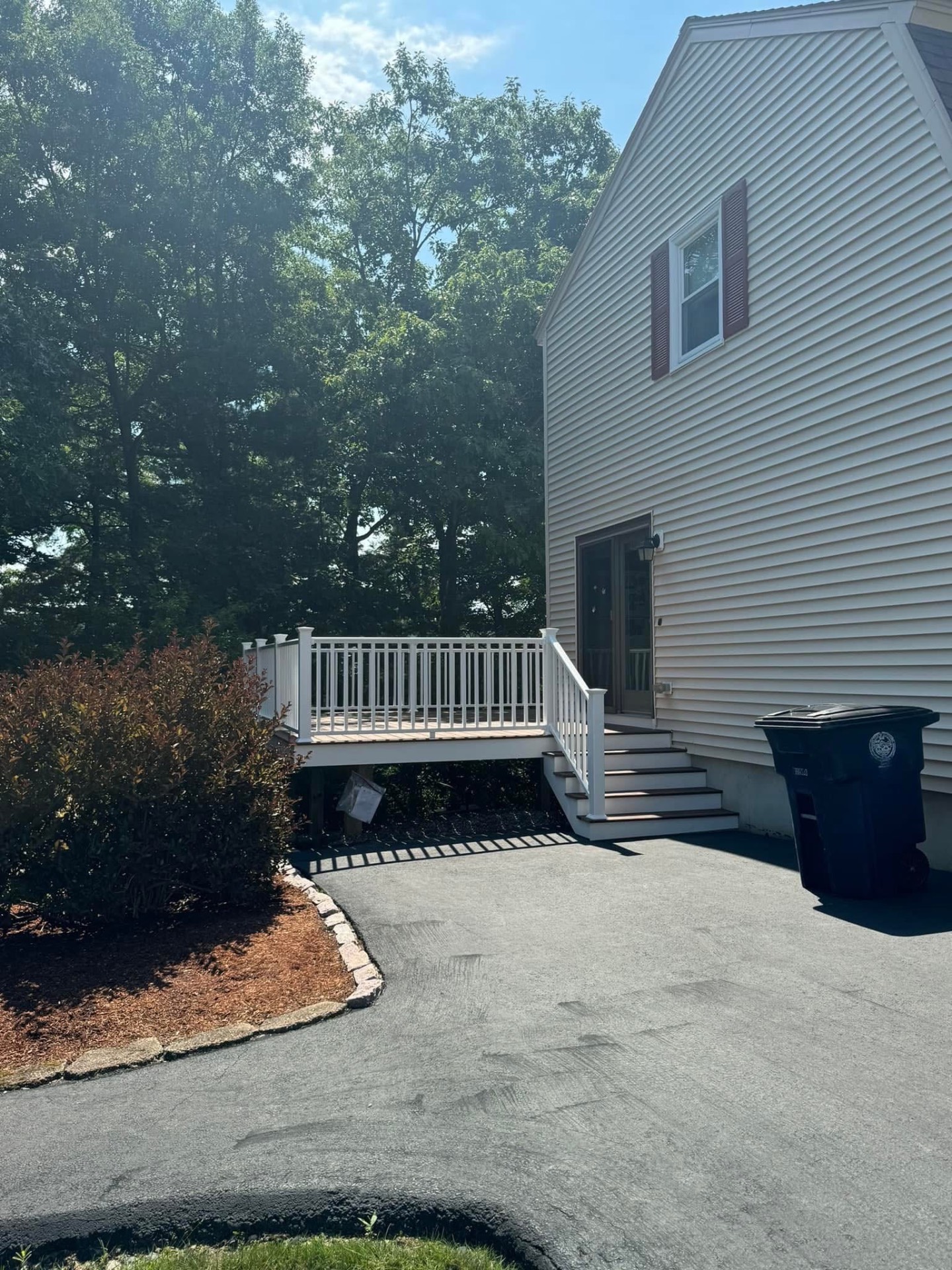 Driveway side — new stairs, wrapped fascia, and clean white railings tie into the home's existing trim.