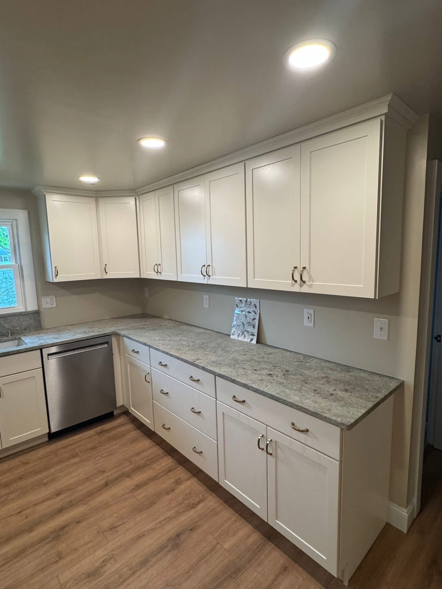 Long run of counter and upper cabinets with granite tops and brushed nickel hardware.