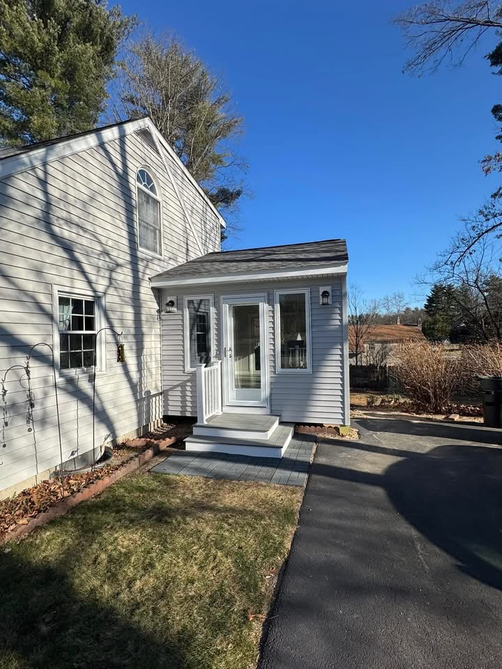 Finished side mudroom entry with gray siding, white trim, and a new stoop.