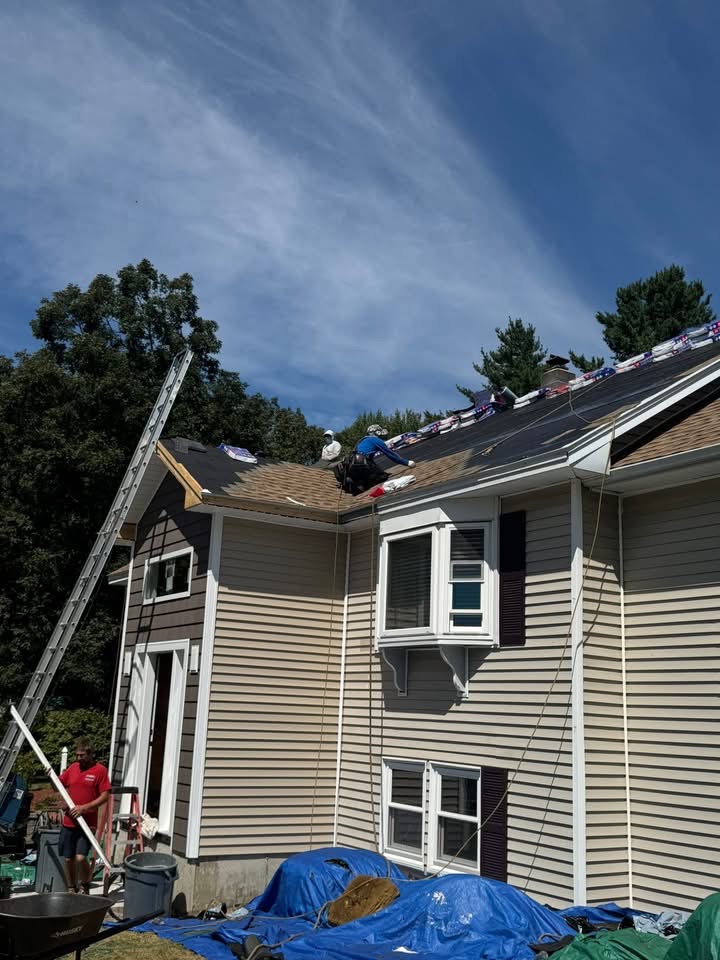 Reroof in progress — tearing off old shingles and installing new architectural shingles across the entire house.