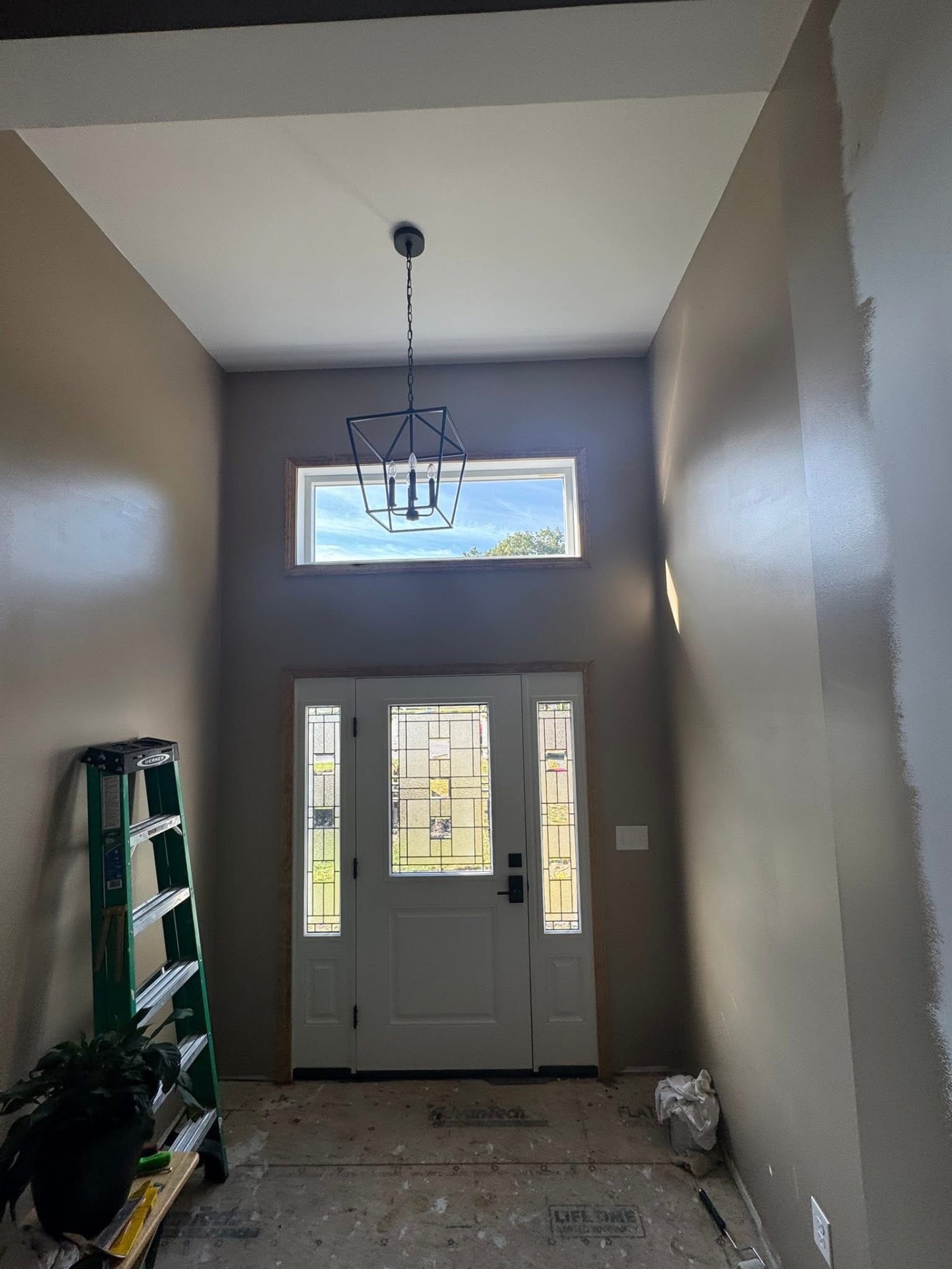 Two-story foyer interior with lantern chandelier, transom window, and stained-glass front door with sidelights.