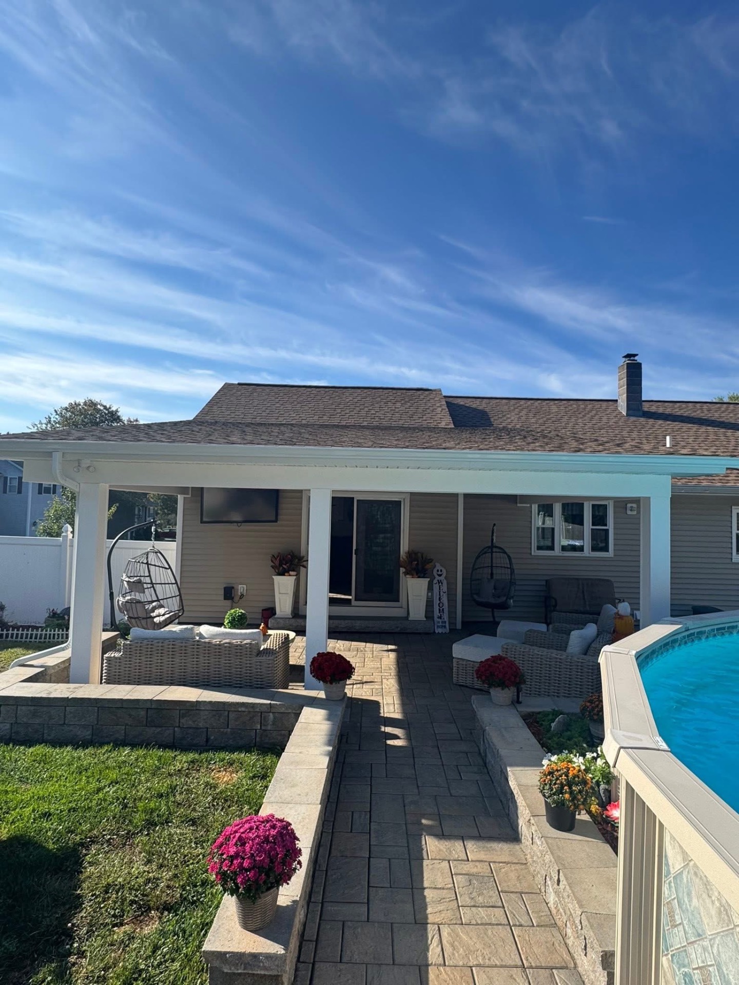 Covered back porch overlooking the pool, with white posts, wrapped fascia, and new architectural shingles above.